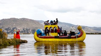 Eine bunte, traditionelle Bootsfahrt auf dem Titicacasee mit fröhlichen Passagieren und malerischer Berglandschaft im Hintergrund.