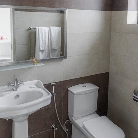 Ein modernes Badezimmer mit einem Waschbecken und einer Toilette, umgeben von hellen Fliesen in neutralen Farben.