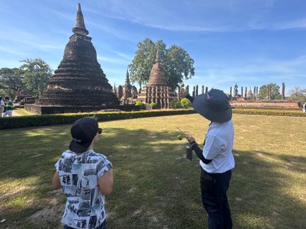 Lokaler Guide führt Touristen durch die Tempelruinen des Wat Mahathat in Sukhothai - Thailand mit Kindern