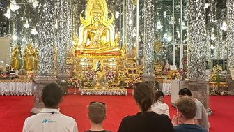 Familie schuat kniend auf den goldenen Buddha im Kristalltempel in Uthai Thani - Thailand mit Kindern