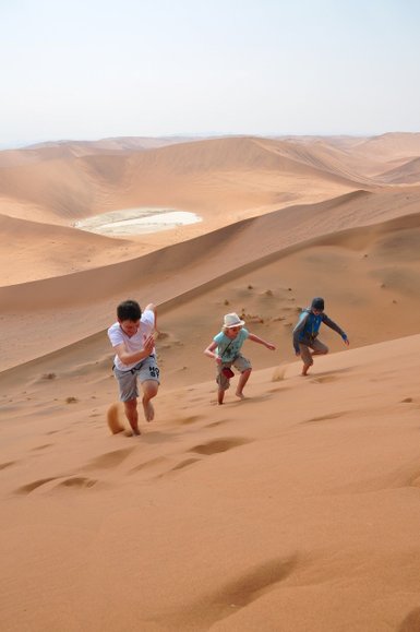 Drei Kinder laufen eine Düne hinauf - Namibia Rundreise mit Kindern