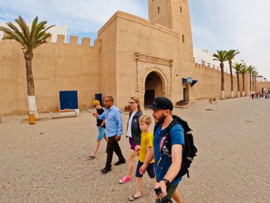 Familie spaziert durch die Straßen von Essaouira, umgeben von braunen Gebäuden – Marokko mit Kindern