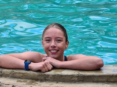 Mädchen genießt den Pool und lächelt – Tansania Reise mit Kindern