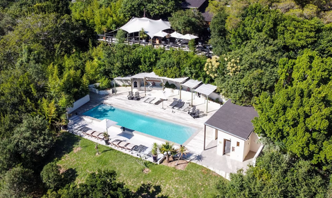Ein luftiger Blick auf einen einladenden Pool, umgeben von üppigem Grün und modernen Liegen, ideal für Entspannung.