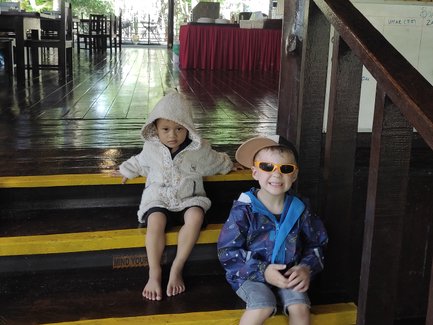 Zwei Kinder sitzen entspannt auf einer Treppe im Restaurant – Malaysia & Borneo Familienreise