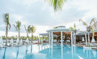 Ein luxuriöser Poolbereich mit Palmen und Liegen, umgeben von einem eleganten Restaurant in Mauritius.