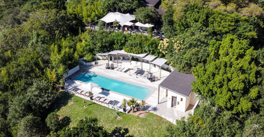 Ein luftiger Blick auf einen einladenden Pool, umgeben von üppigem Grün und modernen Liegen, ideal für Entspannung.