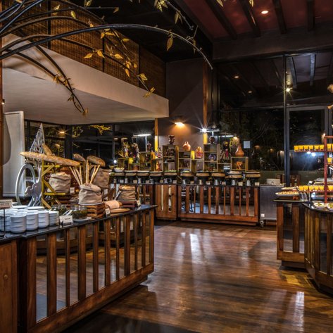 Ein stilvolles Restaurant mit Holzregalen, die eine Vielzahl von Speisen und Getränken präsentieren, umgeben von warmem Licht.