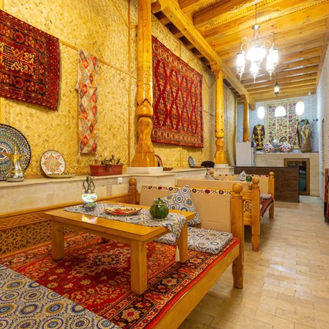 Ein gemütlicher Lounge-Bereich mit bunten Teppichen und traditionellen Wanddekorationen, der einladend wirkt.