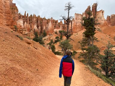 Ein Junge mit einer roten und blauen Jacke wandert auf einem Pfad durch die beeindruckenden Felsformationen des Bryce Canyon.