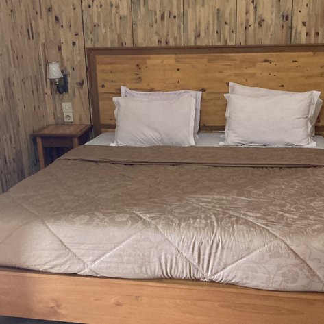 Ein gemütliches Schlafzimmer mit einem großen Holzbett, umgeben von rustikalen Holzpaneelen und sanften Farben.
