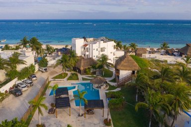 Ein Blick auf das Hotel Ojo de Agua, umgeben von Palmen und einem einladenden Pool, mit dem Meer im Hintergrund.