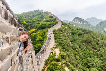 Teenager grüßt von der Großen Mauer mit weitem Blick auf die Landschaft Chinas – China Reise mit Kindern