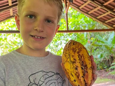 Junge zeigt stolz eine Kakaopflanze bei der Schokoladentour im Tirimbina Reservat – Costa Rica Familienreise
