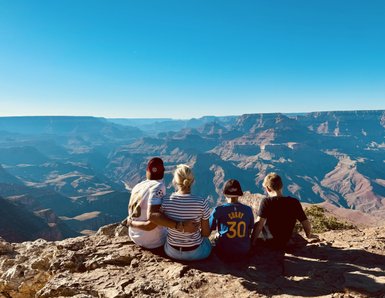Eine Gruppe von vier Personen sitzt am Rand des Grand Canyon und genießt die atemberaubende Aussicht auf die Landschaft.