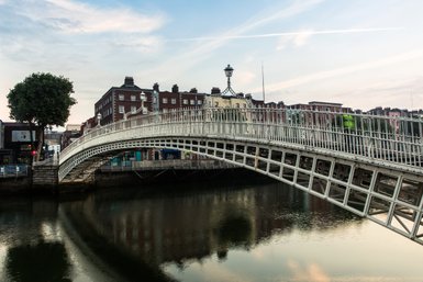 Eine elegante Brücke mit geschwungenem Design über einem ruhigen Fluss, umgeben von historischen Gebäuden in Dublin.