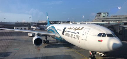 Ein Oman Air Flugzeug steht am Flughafen, bereit für den nächsten Flug, unter einem klaren blauen Himmel.