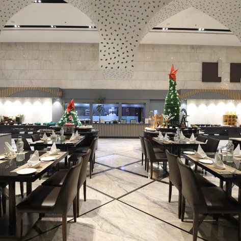 Ein elegantes Restaurant mit festlich dekorierten Weihnachtsbäumen und stilvoll gedeckten Tischen für ein besonderes Essen.