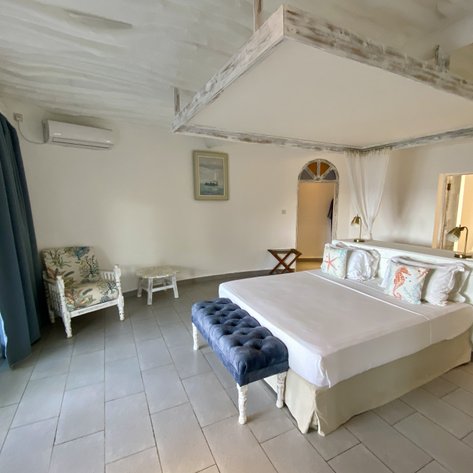 Ein helles, modernes Zimmer mit einem großen Bett, einem gemütlichen Sessel und einem kleinen Tisch, ideal für Entspannung.