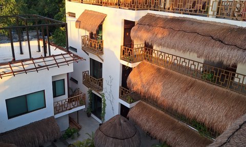 Ein modernes Hotel mit Strohdächern, umgeben von üppigem Grün und einem einladenden Pool im Innenhof.