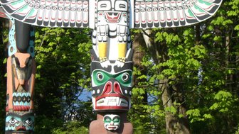 Im Stanley Park stehen mehrere farbenfrohe Totempfähle, die traditionelle indigene Kunst darstellen und die Natur umgeben.
