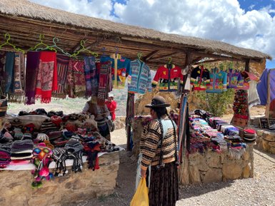 Ein Marktstand mit bunten Textilien und handgefertigten Accessoires, umgeben von einer malerischen Landschaft.