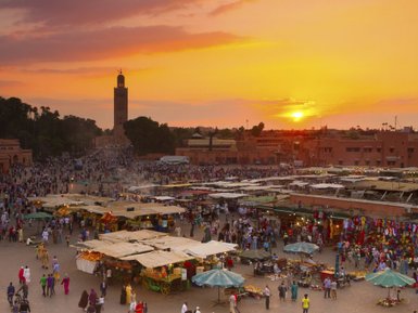 Djemaa el Fna Platz mit Menschen und Marktständen im Licht des Sonnenuntergangs in Marrakesch – Marokko Reise mit Kindern