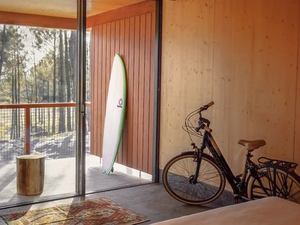 Ein modernes Hotelzimmer mit Holzverkleidung, einem Surfbrett an der Wand und einem Fahrrad in der Ecke.