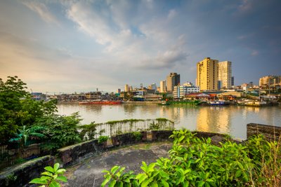 Ein Blick auf den ruhigen Fluss, umgeben von modernen Gebäuden und üppigem Grün, das die Stadt Manila charakterisiert.