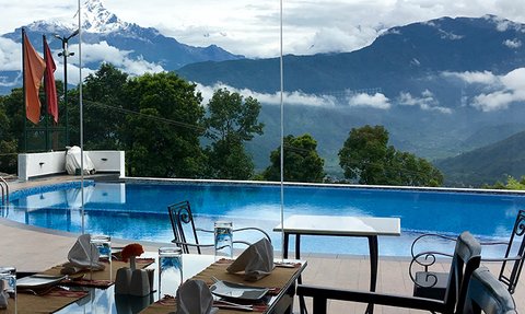 Ein eleganter Essbereich mit Blick auf einen glitzernden Pool und majestätische Himalaya-Berge im Hintergrund.