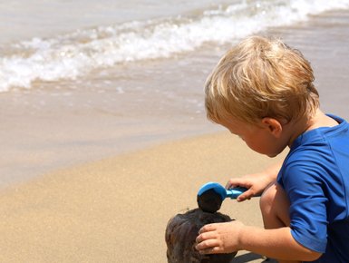 Kleines Kind spielt fröhlich im Sand am Strand – Costa Rica Familienreise