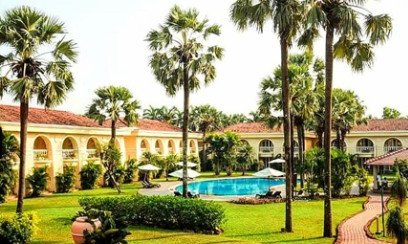 Ein luxuriöses Resort in Goa mit einem einladenden Pool, umgeben von üppigem Grün und hohen Palmen.
