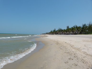 Ein ruhiger Strand mit feinem Sand, sanften Wellen und einer klaren blauen Himmel, ideal für einen entspannten Tag am Meer.