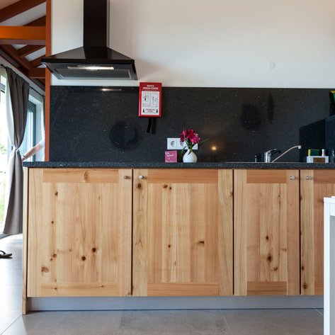 Eine moderne Küche mit Holzschränken, schwarzer Arbeitsplatte und frischen Blumen auf dem Tisch, die einladend wirkt.