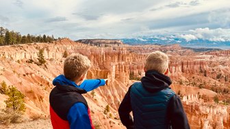 Zwei Jungen stehen am Rand des Bryce Canyon und betrachten die beeindruckenden Felsformationen in der Ferne.