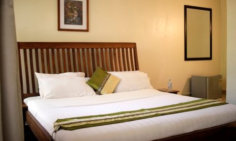 Ein gemütliches Hotelzimmer mit einem großen Bett, dekoriert mit Kissen und einem grünen Überwurf auf der Bettdecke.