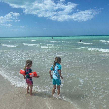 Kinder planschen am Ufer und schauen auf das Meer – Mexiko mit Kindern