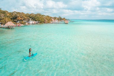 Teenagerin auf einem Paddleboard auf dem türkisfarbenen Wasser der Lagune von Bacalar – Mexiko mit Kindern