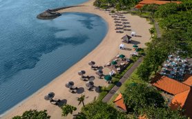Ein malerischer Strand mit Sonnenliegen und Sonnenschirmen, umgeben von üppigem Grün und klarem Wasser.