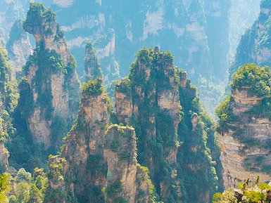 Majestätische, hoch aufragende Felsen umgeben von üppigem Grün und Nebel, die die beeindruckende Landschaft des Nationalparks zeigen.