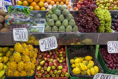 Ein bunter Marktstand mit einer Vielzahl von frischen Früchten, darunter Äpfel, Trauben und exotische Früchte wie Drachenfrucht.