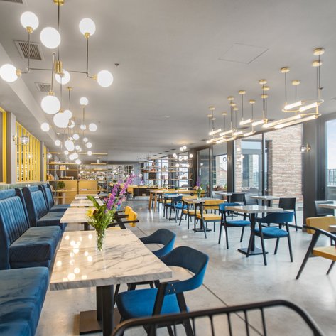 Ein modernes Restaurant mit eleganten blauen Bänken und hellen Tischen, das eine einladende Atmosphäre ausstrahlt.