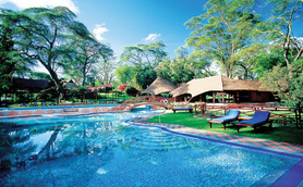 Ein glitzernder Pool spiegelt die üppige grüne Landschaft und die blauen Himmel über dem Lake Naivasha Resort wider.