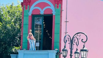 Ein bunter Balkon in Buenos Aires zeigt eine Statue eines Fußballspielers, der einen Pokal triumphierend in die Höhe hält.