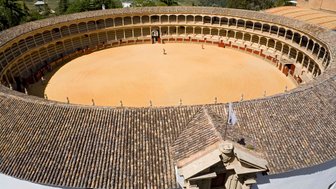 Die Stierkampfarena in Ronda zeigt eine beeindruckende, kreisförmige Struktur mit einem sandigen Innenbereich und umlaufenden Sitzplätzen.