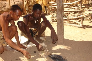 Ein Mann entzündet ein Feuer - Namibia mit Jugendlichen