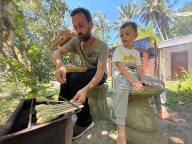 Reisender und sein Kind bereiten gemeinsam balinesische Speisen am Grill zu – Bali Familienreise