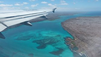Ein Blick aus dem Flugzeug auf die atemberaubende Küste der Galapagos-Inseln mit klarem, türkisfarbenem Wasser.