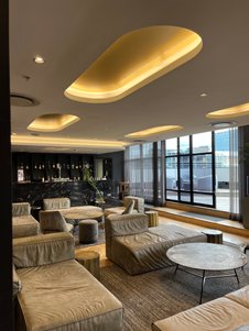 Ein eleganter Lobbybereich mit bequemen, hellen Sofas und einem stilvollen Tisch, umgeben von großen Fenstern.