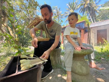 Reisender und sein Kind bereiten gemeinsam balinesische Speisen am Grill zu – Bali Familienreise